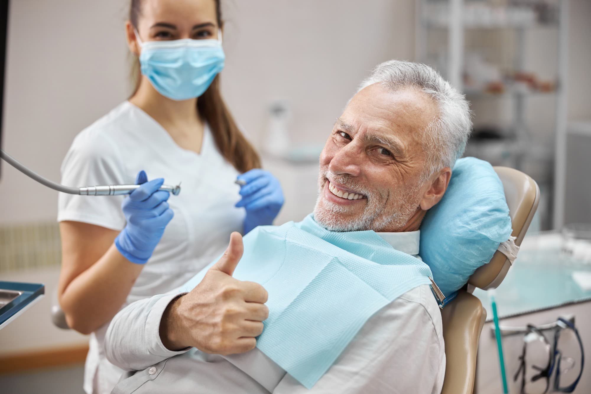 A smiling patient giving a thumbs-up from the dental chair